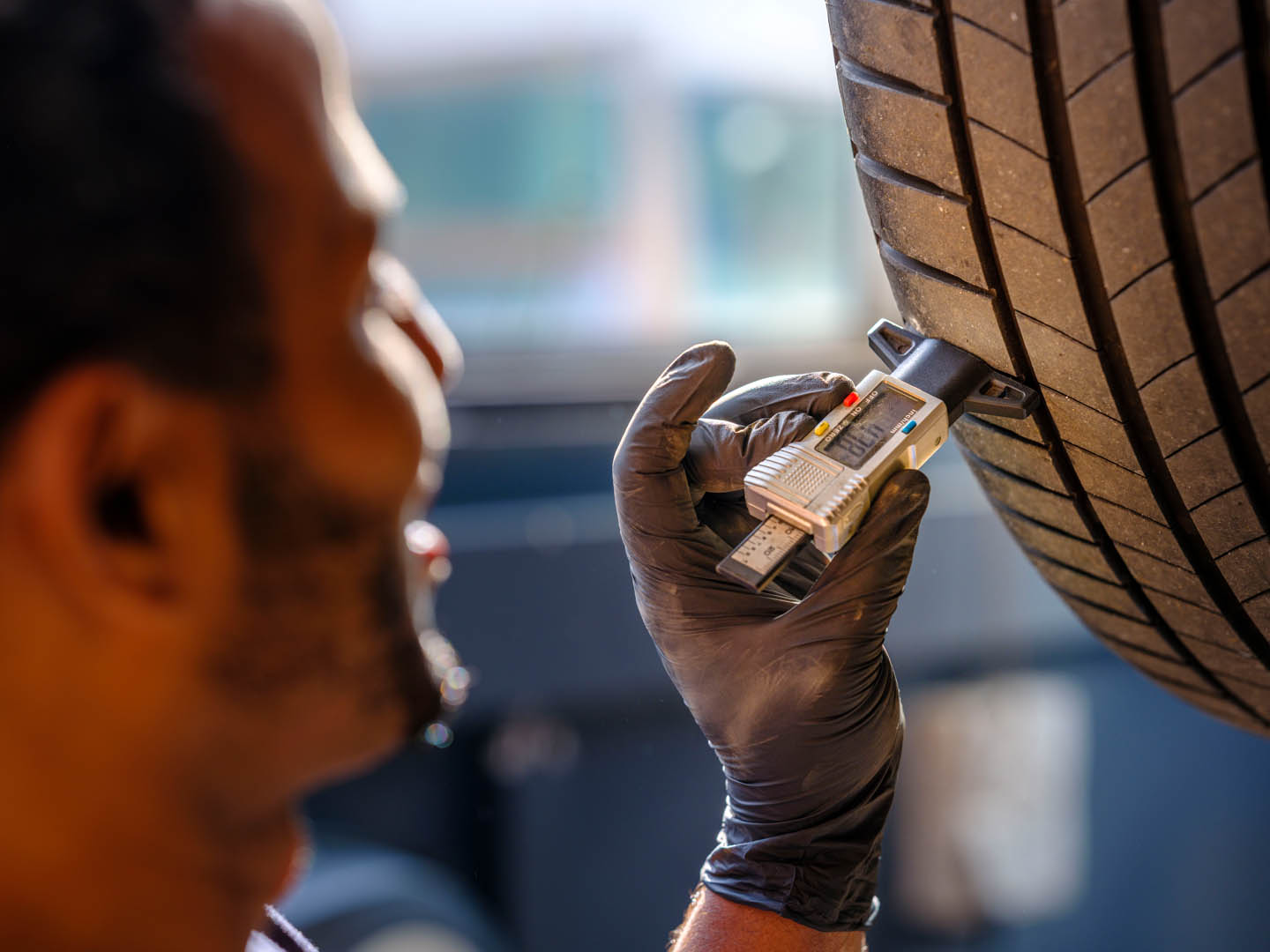 Ein Werkstatt-Service Mitarbeiter des Autohaus Spratter misst die Profiltiefe eines Autoreifens