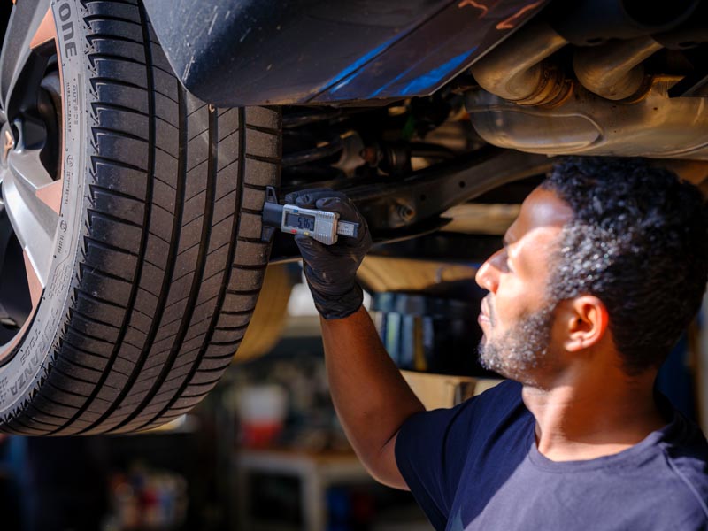 Ein Mitarbeiter des Service Teams führt eine Inspektion an einem Autoreifen durch in der Werkstatt des SEAT Und Cupra-Service Partners Autohaus Spratter, München