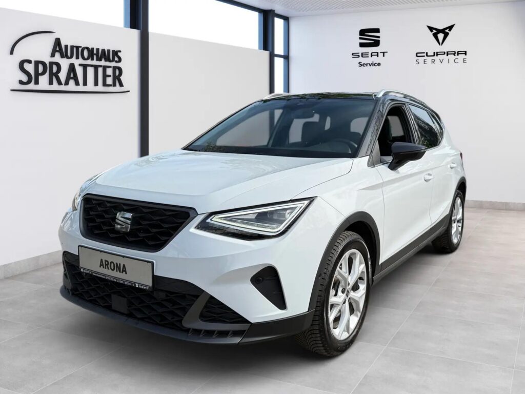 Ein weisser SEAT Arona steht im Ausstellungsraum des Autohaus Spratter vor einem SEAT und CUPRA Service Schild